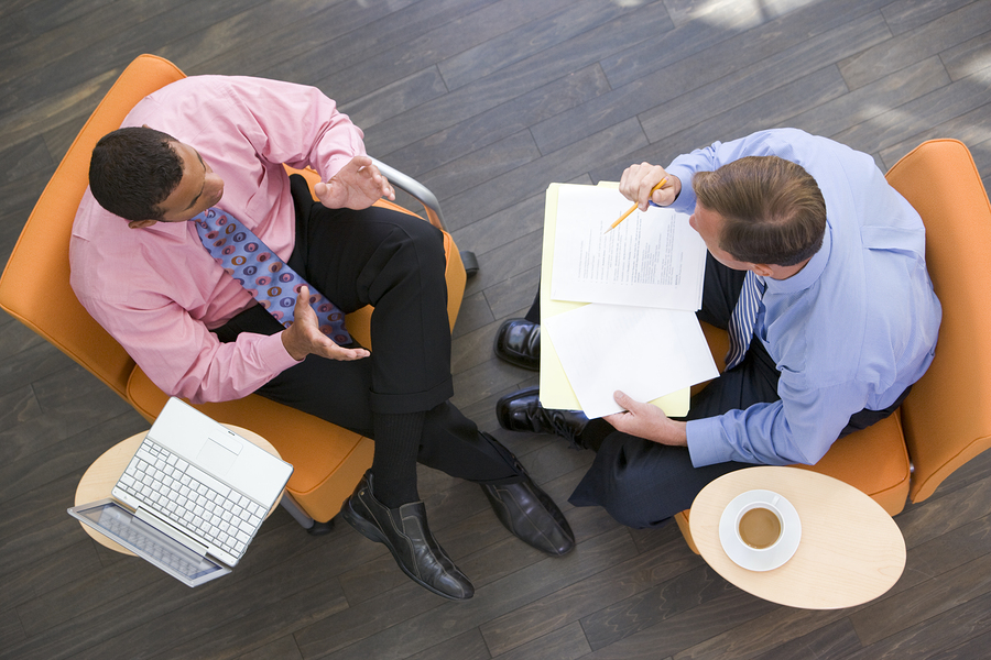 Two Businessmen Sitting Indoors With Coffee Laptop And Folder